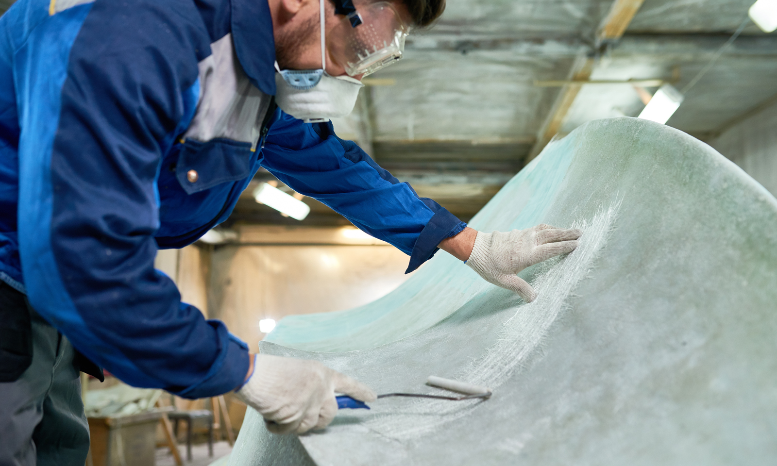 Mann jobber med glassfiber i verksted